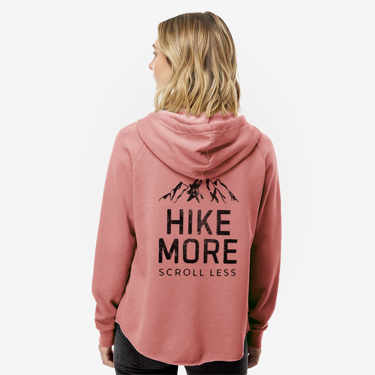 Woman wearing a dusty rose women's Cali Wave zip-up sweatshirt printed with black mountain peaks above the bold words Hike More, Scroll Less, seen from behind.