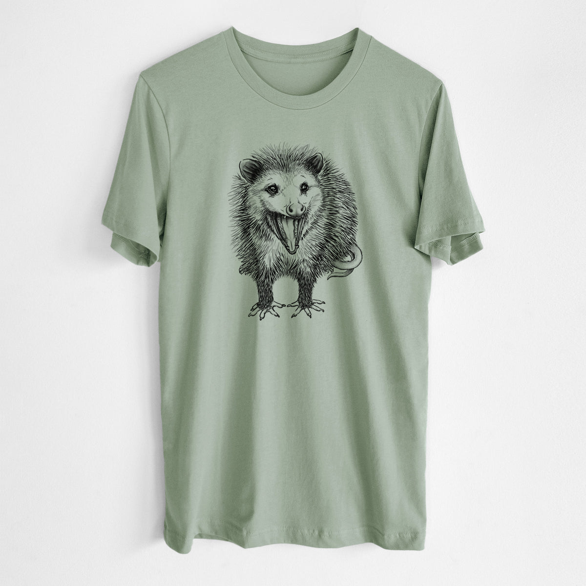 Sage green lightweight cotton t-shirt laid flat, printed with a detailed black ink illustration of an opossum standing and facing forward, mouth open wide in a hiss, with shaggy fur and its tail curled behind.