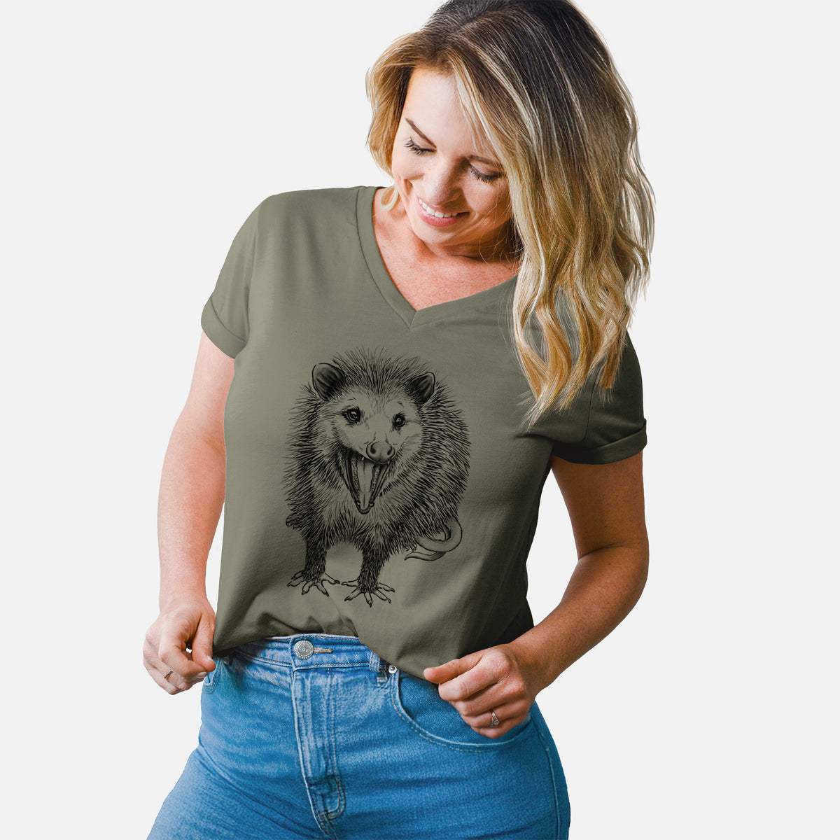 Woman wearing a military green women's relaxed fit cotton V-neck t-shirt printed with a detailed black ink illustration of an opossum standing and facing forward, mouth open wide in a hiss, with shaggy fur and its tail curled behind.