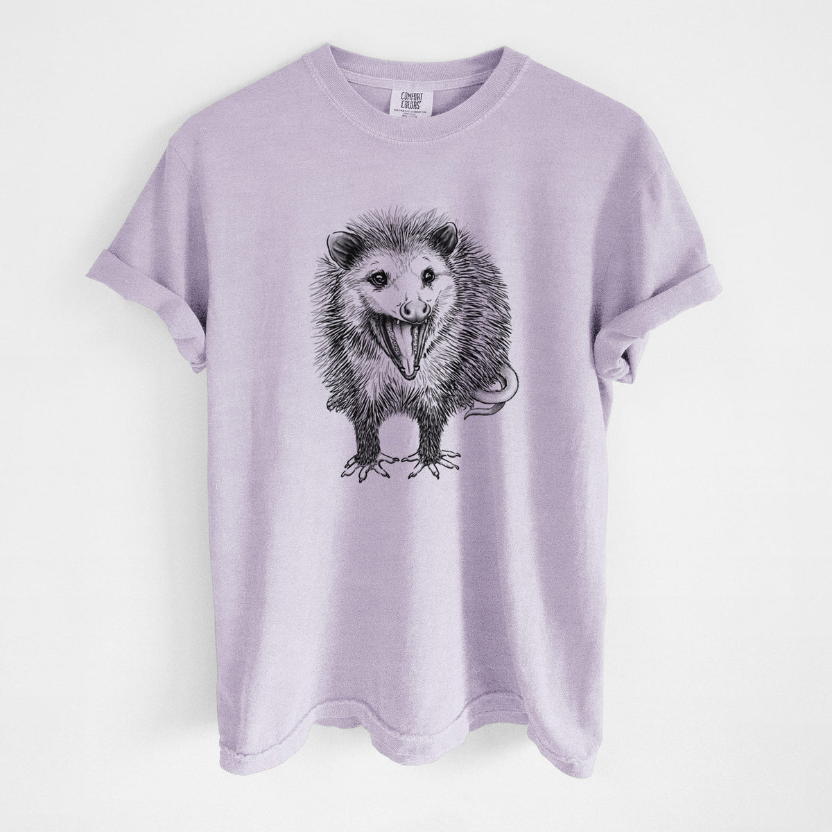 Orchid purple Comfort Colors t-shirt laid flat, printed with a detailed black ink illustration of an opossum standing and facing forward, mouth open wide in a hiss, with shaggy fur and its tail curled behind.
