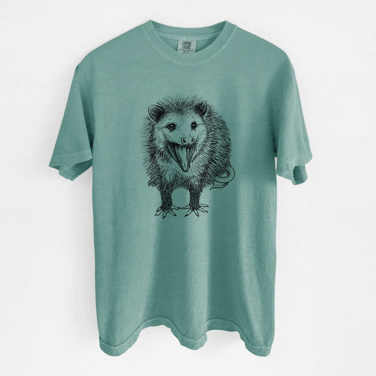 Reef green Comfort Colors t-shirt laid flat, printed with a detailed black ink illustration of an opossum standing and facing forward, mouth open wide in a hiss, with shaggy fur and its tail curled behind.