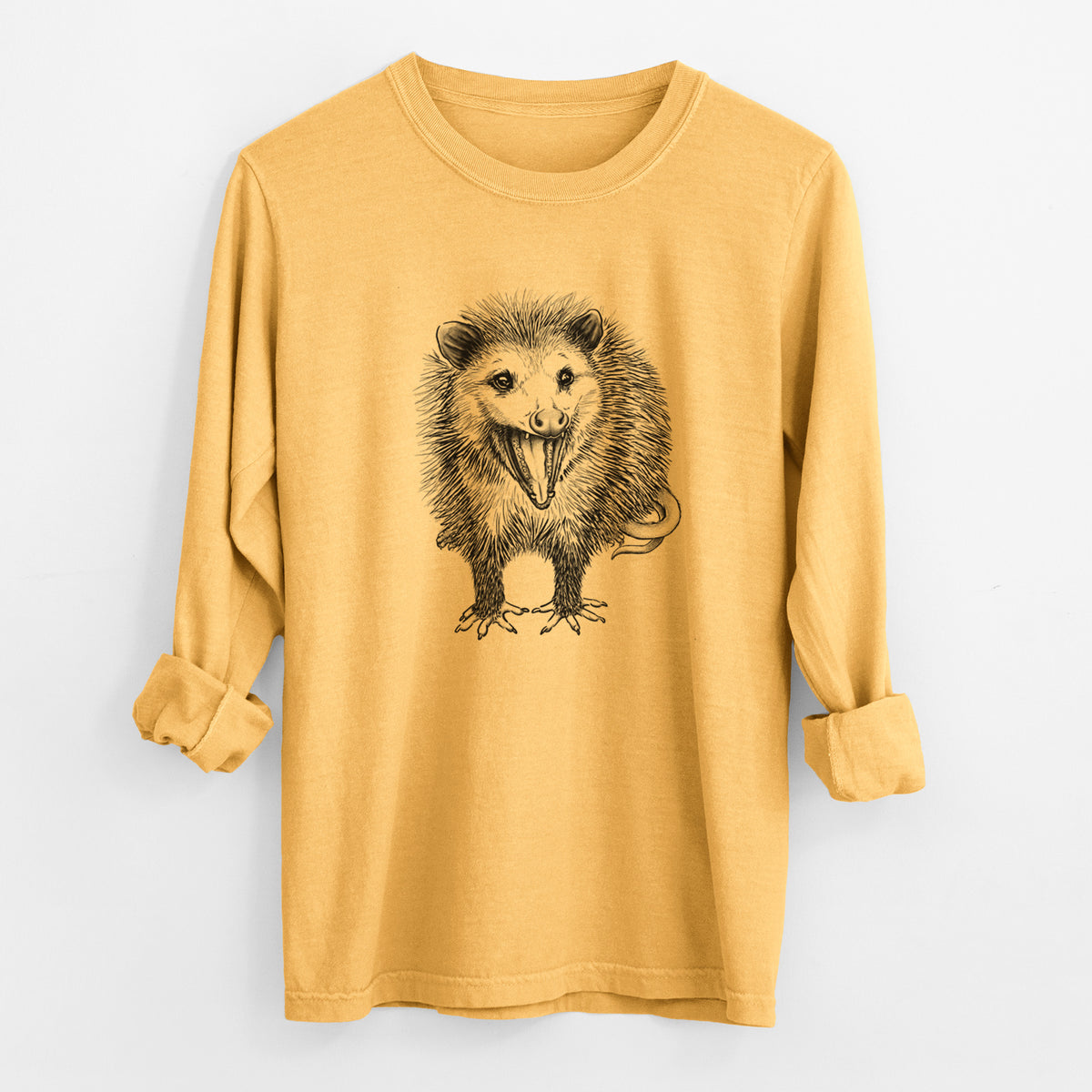 Golden wheat yellow Comfort Colors long sleeve shirt laid flat with the cuffs rolled, printed with a detailed black ink illustration of an opossum standing and facing forward, mouth open wide in a hiss, with shaggy fur and its tail curled behind.