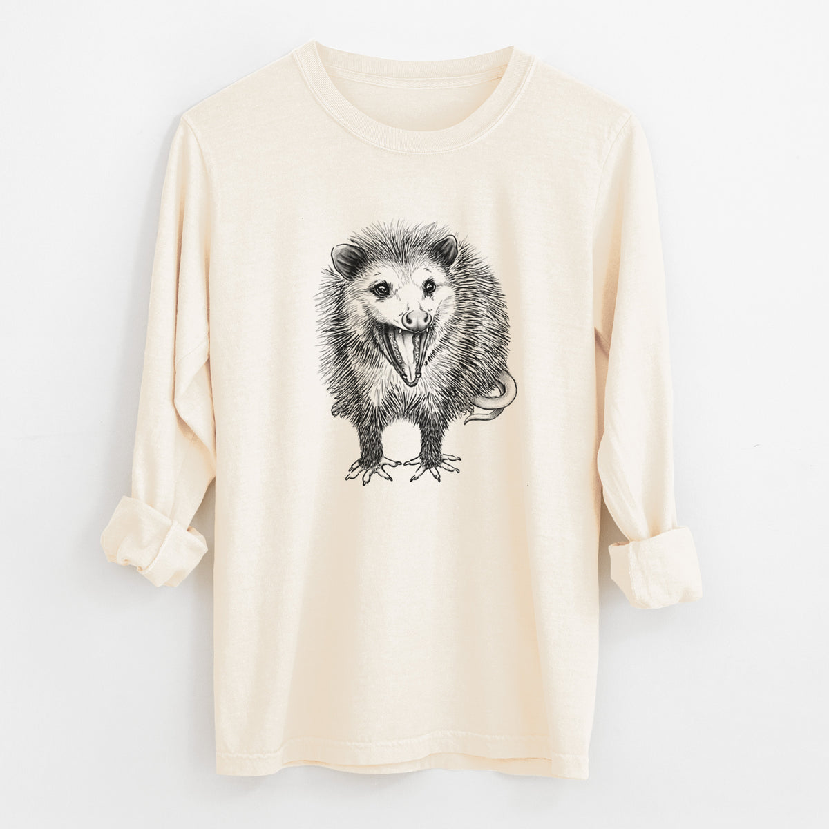 Ivory Comfort Colors long sleeve shirt laid flat with the cuffs rolled, printed with a detailed black ink illustration of an opossum standing and facing forward, mouth open wide in a hiss, with shaggy fur and its tail curled behind.