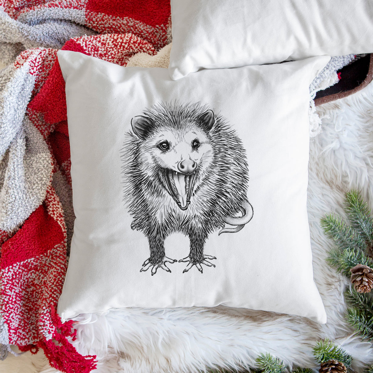 White pillow cover printed with a detailed black ink illustration of an opossum standing and facing forward, mouth open wide in a hiss, with shaggy fur and its tail curled behind, on a woven chair.