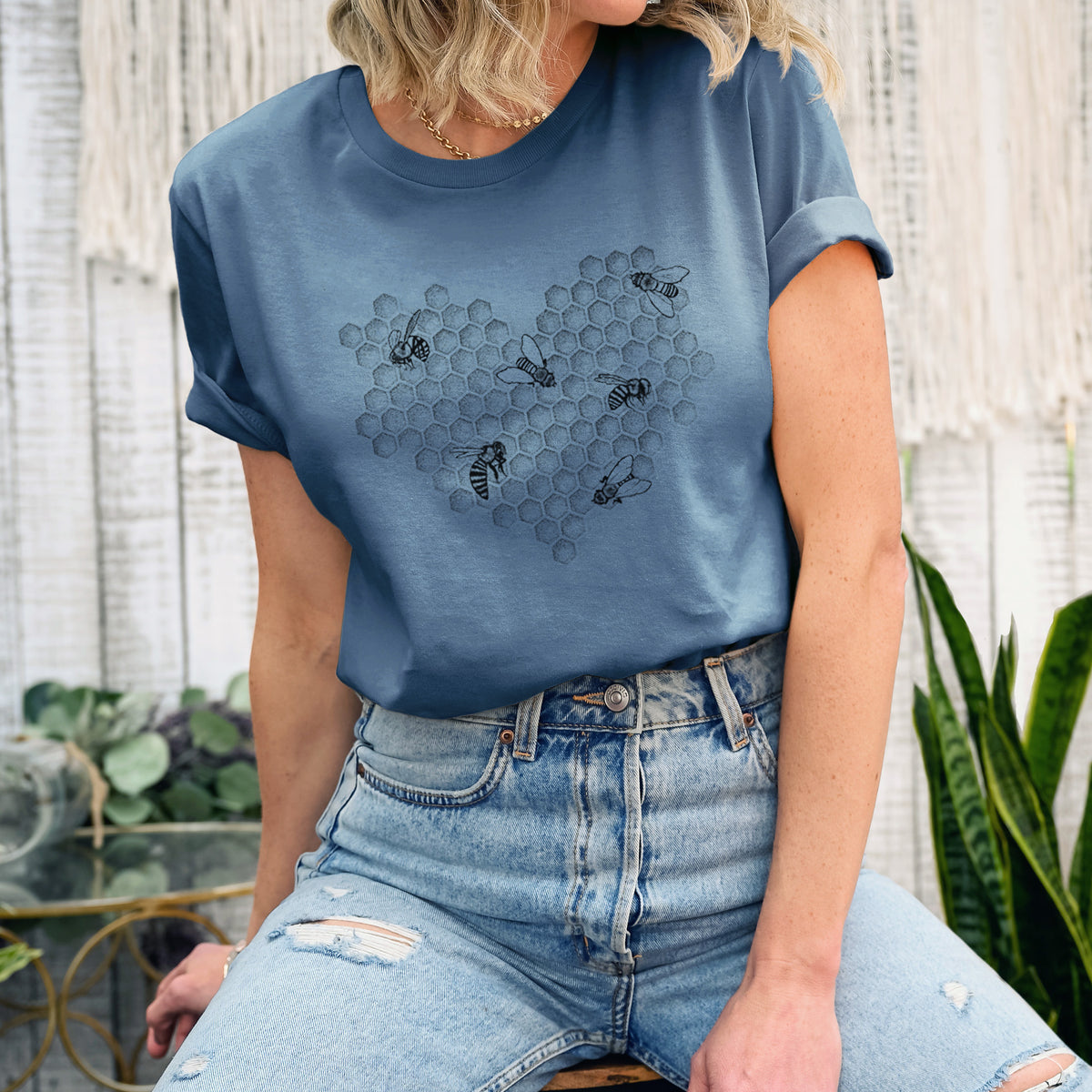 Woman wearing a steel blue lightweight cotton t-shirt printed with a black ink heart made of honeycomb cells with small bees crawling across it.