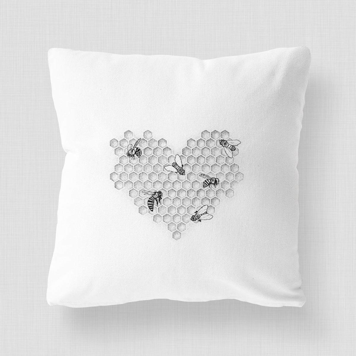 White pillow cover printed with a black ink heart made of honeycomb cells with small bees crawling across it.