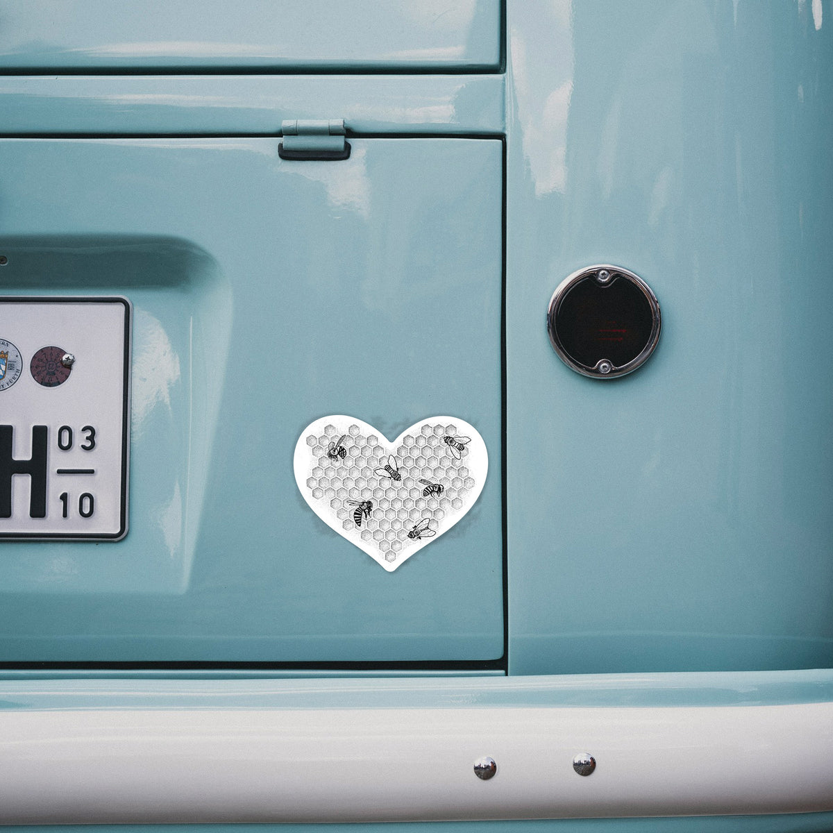 4 inch vinyl decal of a black ink heart made of honeycomb cells with small bees crawling across it on the back of a van.