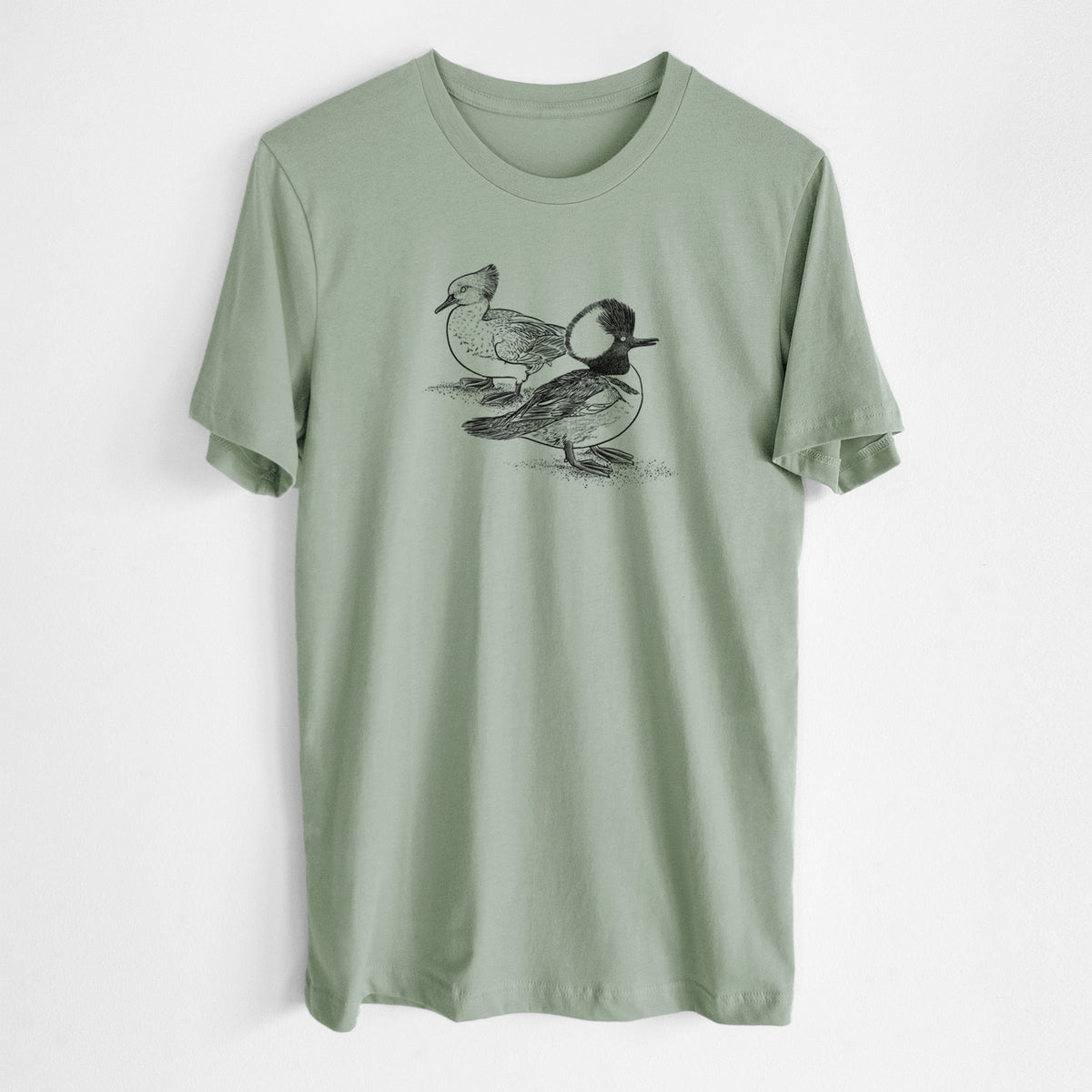 Sage green lightweight cotton t-shirt laid flat, printed with a detailed black ink illustration of a pair of hooded mergansers, male and female.
