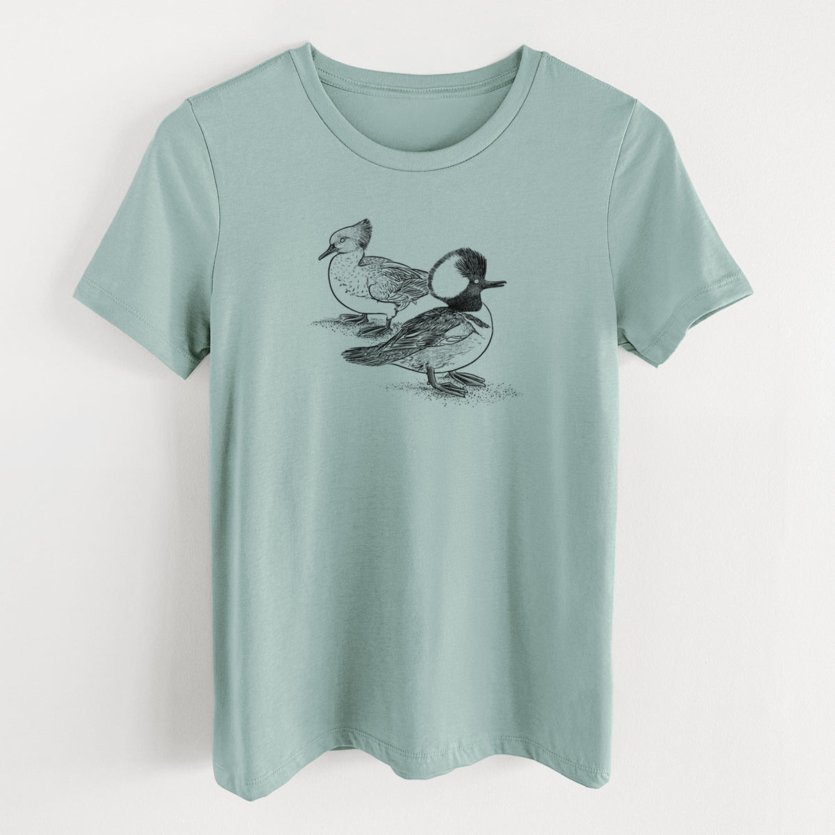 Dusty blue women's relaxed fit cotton t-shirt laid flat, printed with a detailed black ink illustration of a pair of hooded mergansers, male and female.