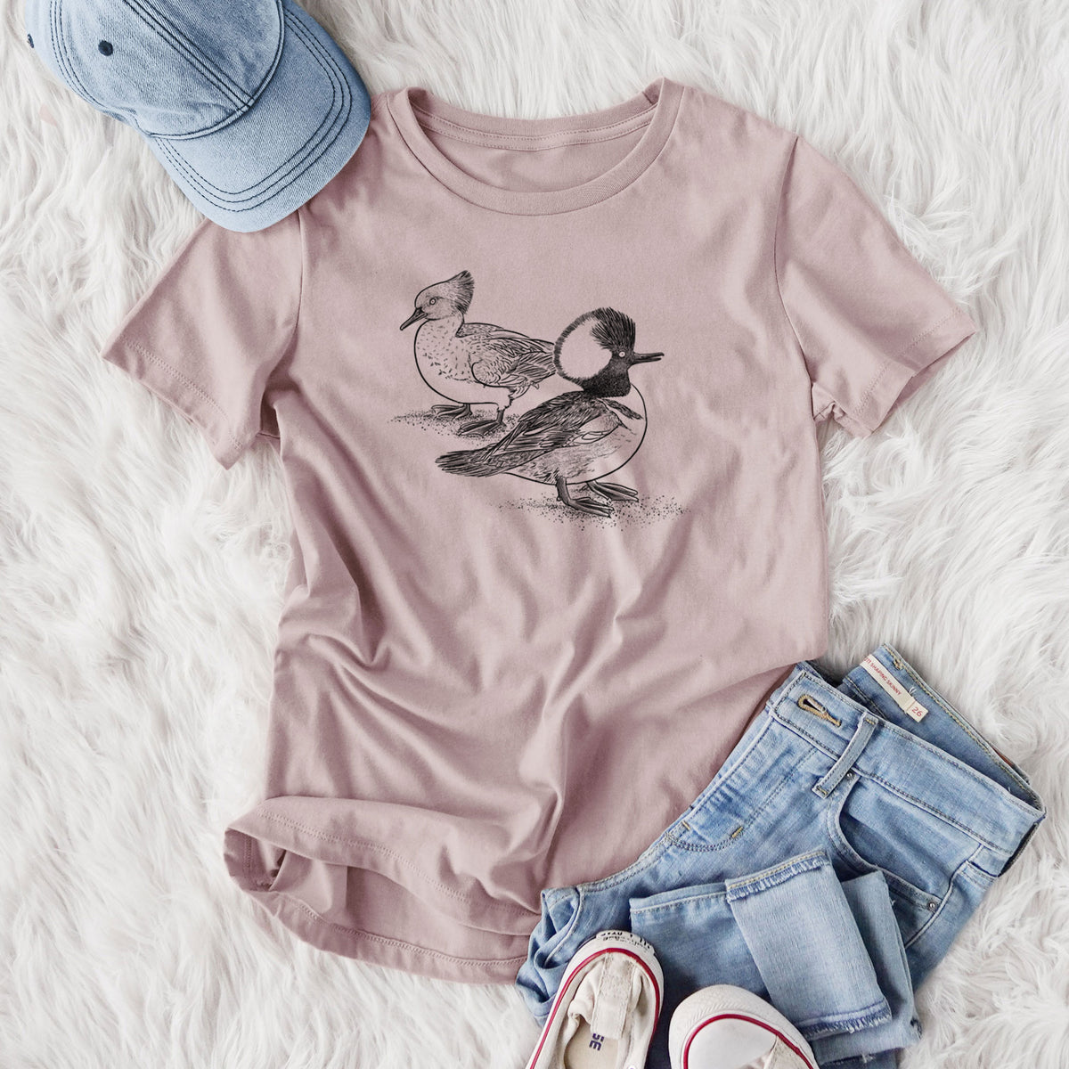 Women's relaxed fit cotton t-shirt printed with a detailed black ink illustration of a pair of hooded mergansers, male and female, styled flat on a white faux fur rug with jeans.