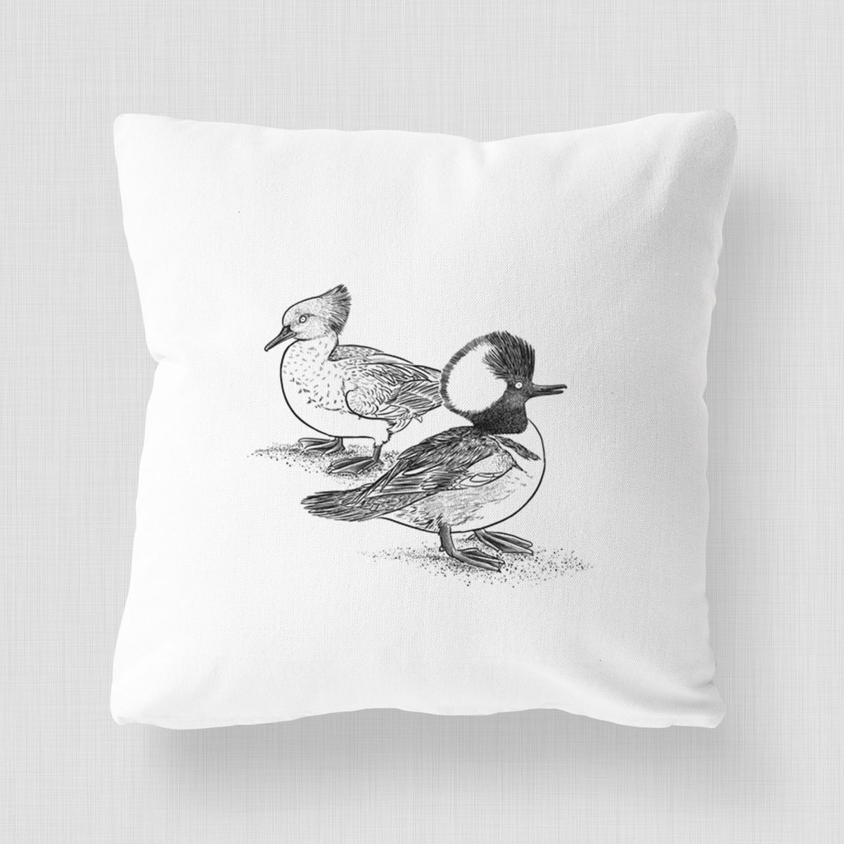 White pillow cover printed with a detailed black ink illustration of a pair of hooded mergansers, male and female.