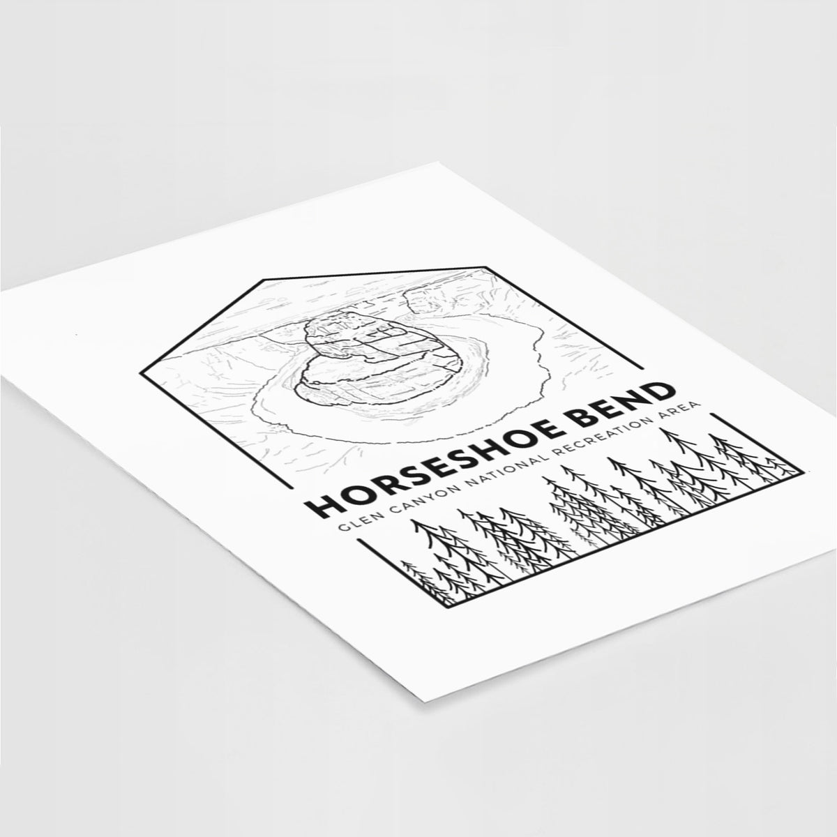 Art print of a black line art badge of Horseshoe Bend above pine trees, with the words Horseshoe Bend, lying at an angle on a white surface.
