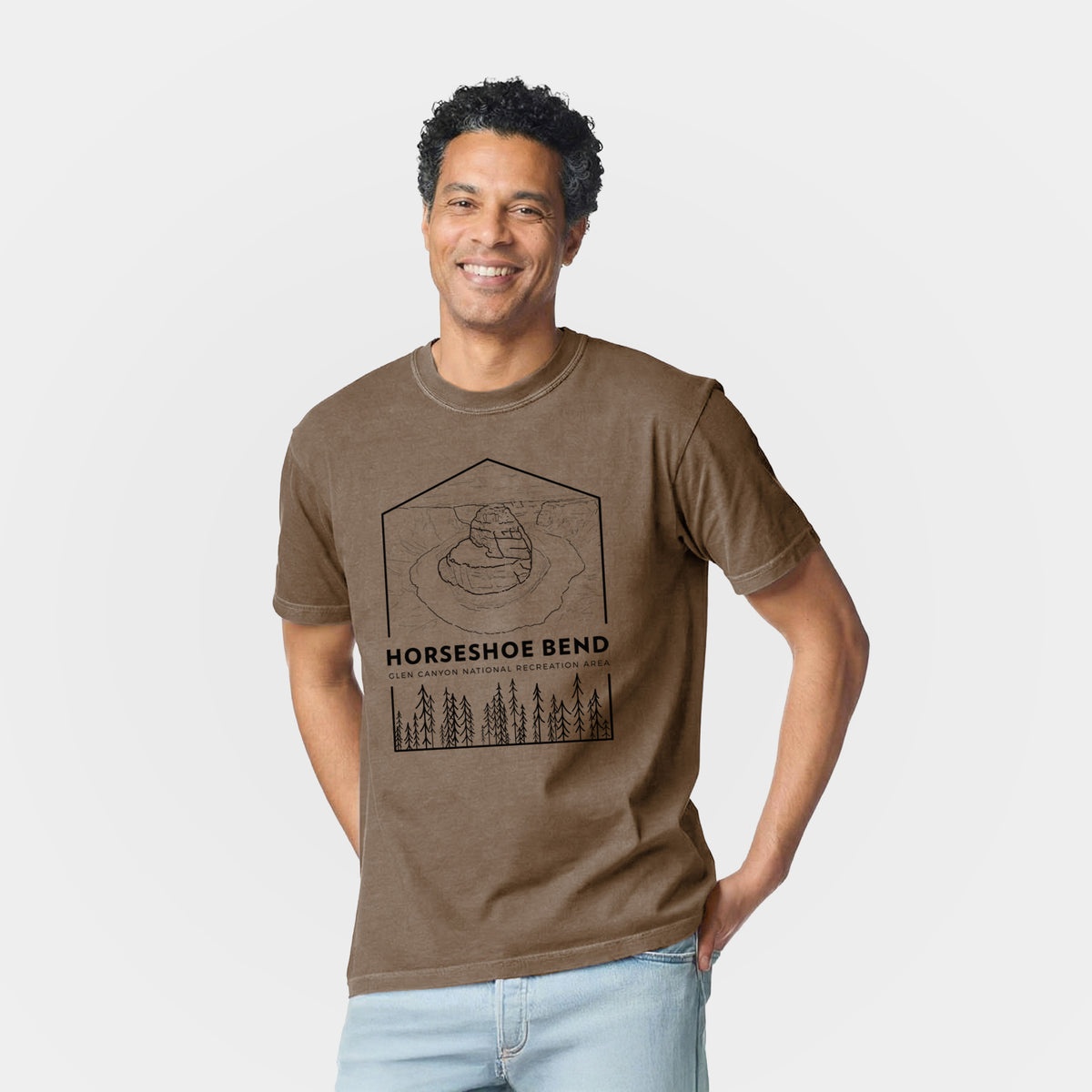 Man wearing a Comfort Colors t-shirt printed with a black line art badge of Horseshoe Bend above pine trees, with the words Horseshoe Bend.