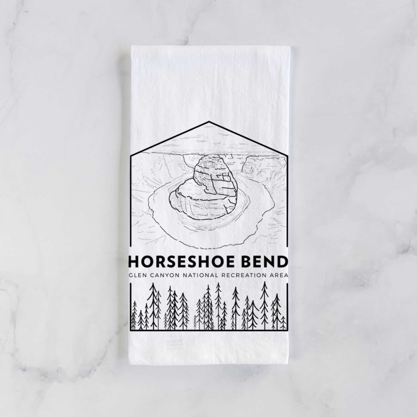 White cotton tea towel printed with a black line art badge of Horseshoe Bend above pine trees, with the words Horseshoe Bend, on a marble counter beside a round wooden cutting board and greenery.