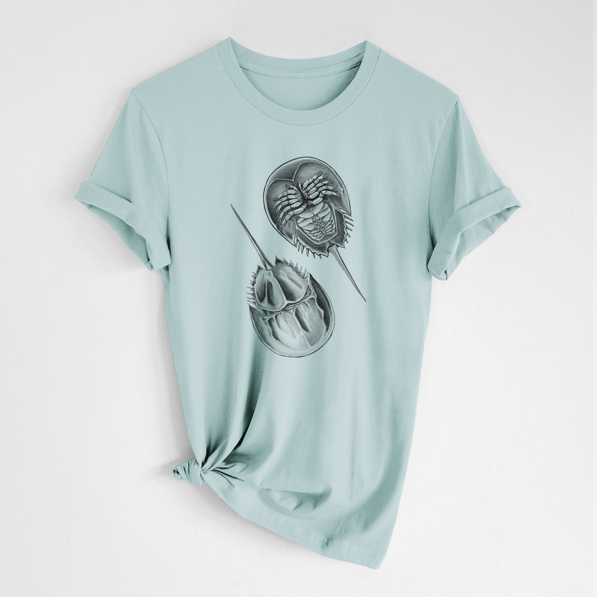 Dusty blue lightweight cotton t-shirt laid flat with the sleeves rolled, printed with a detailed black ink illustration of two horseshoe crabs.