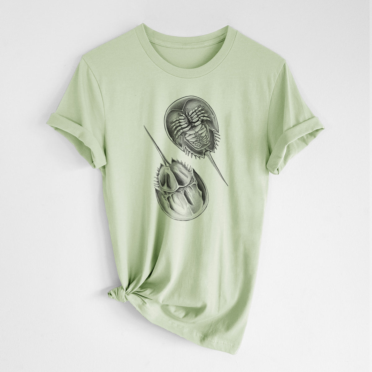 Spring green lightweight cotton t-shirt laid flat with the sleeves rolled, printed with a detailed black ink illustration of two horseshoe crabs.