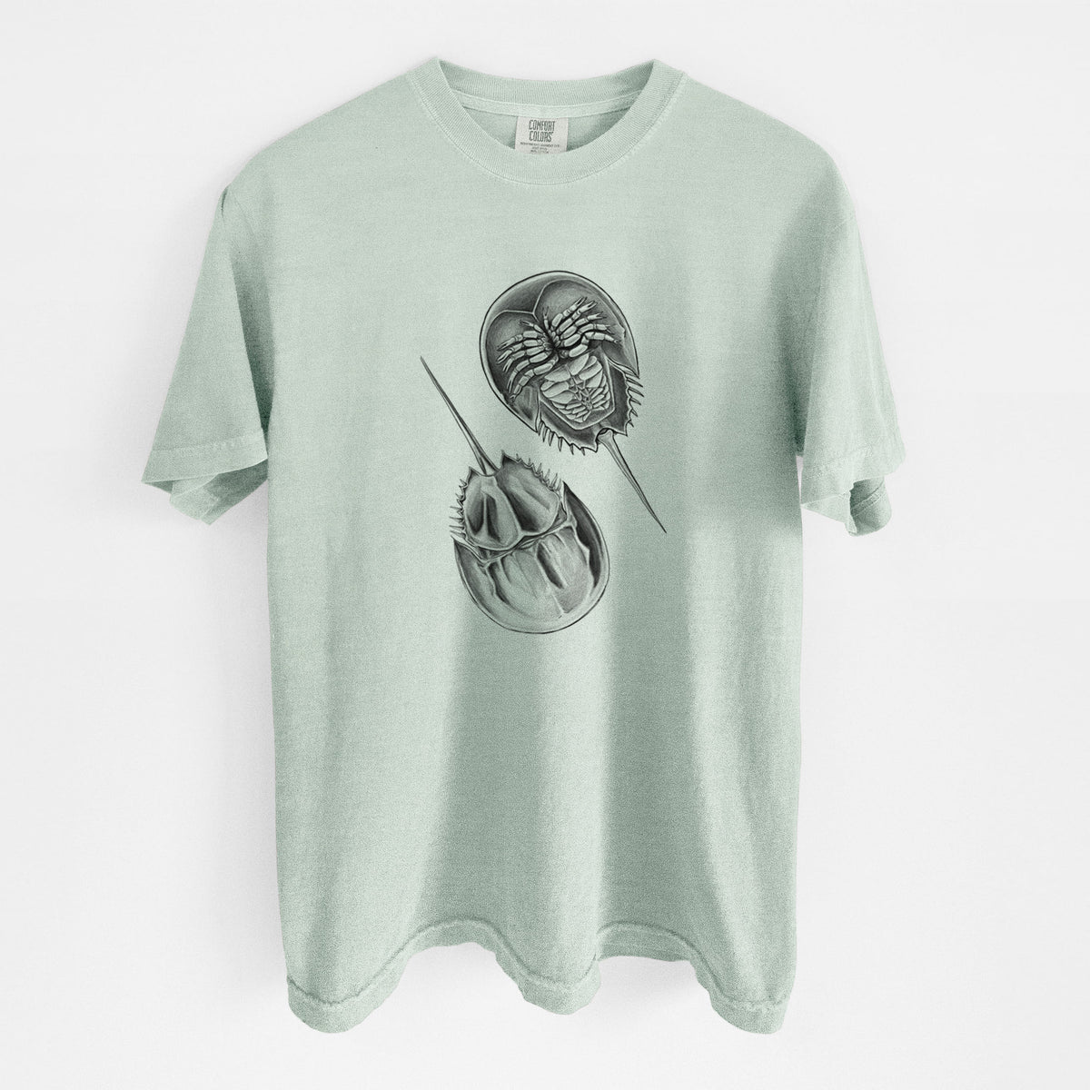 Bay green Comfort Colors t-shirt laid flat, printed with a detailed black ink illustration of two horseshoe crabs.