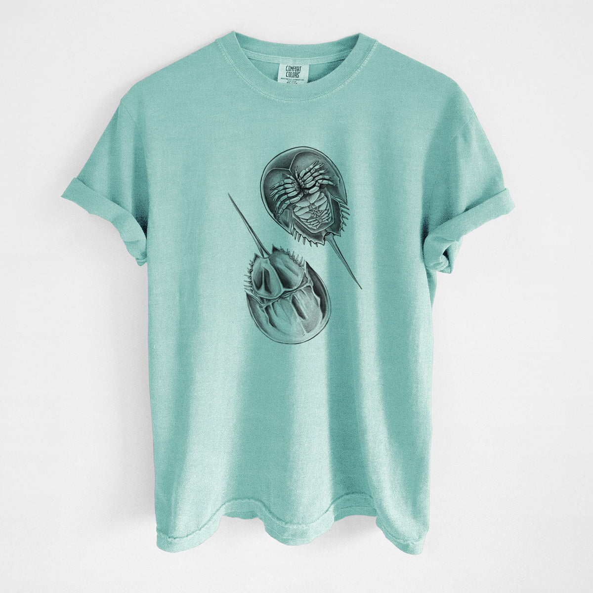 Chalky mint Comfort Colors t-shirt laid flat, printed with a detailed black ink illustration of two horseshoe crabs.