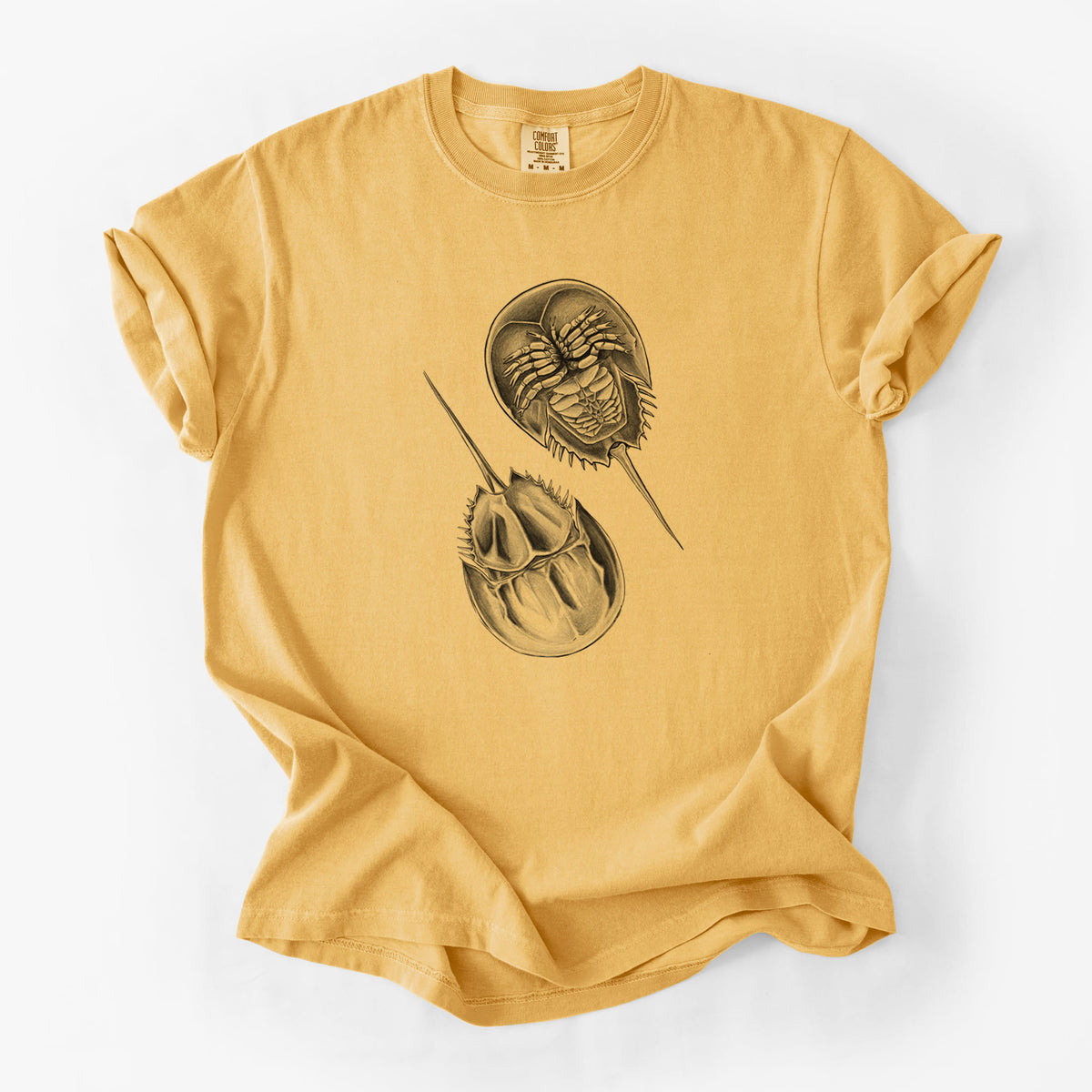Golden wheat yellow Comfort Colors t-shirt laid flat, printed with a detailed black ink illustration of two horseshoe crabs.
