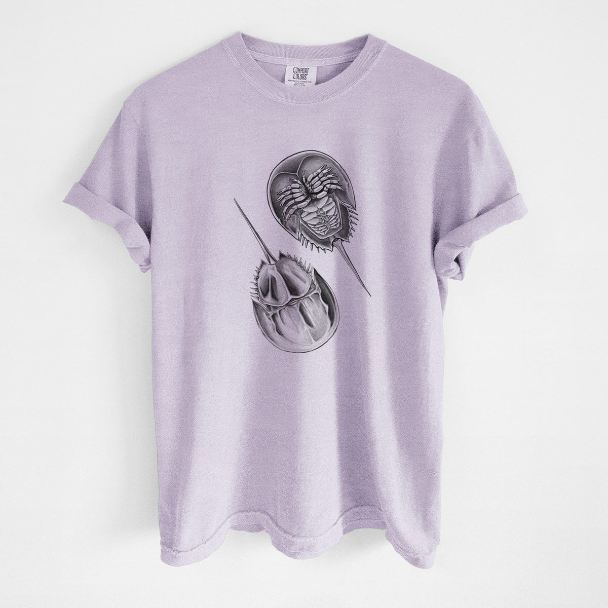 Orchid purple Comfort Colors t-shirt laid flat, printed with a detailed black ink illustration of two horseshoe crabs.
