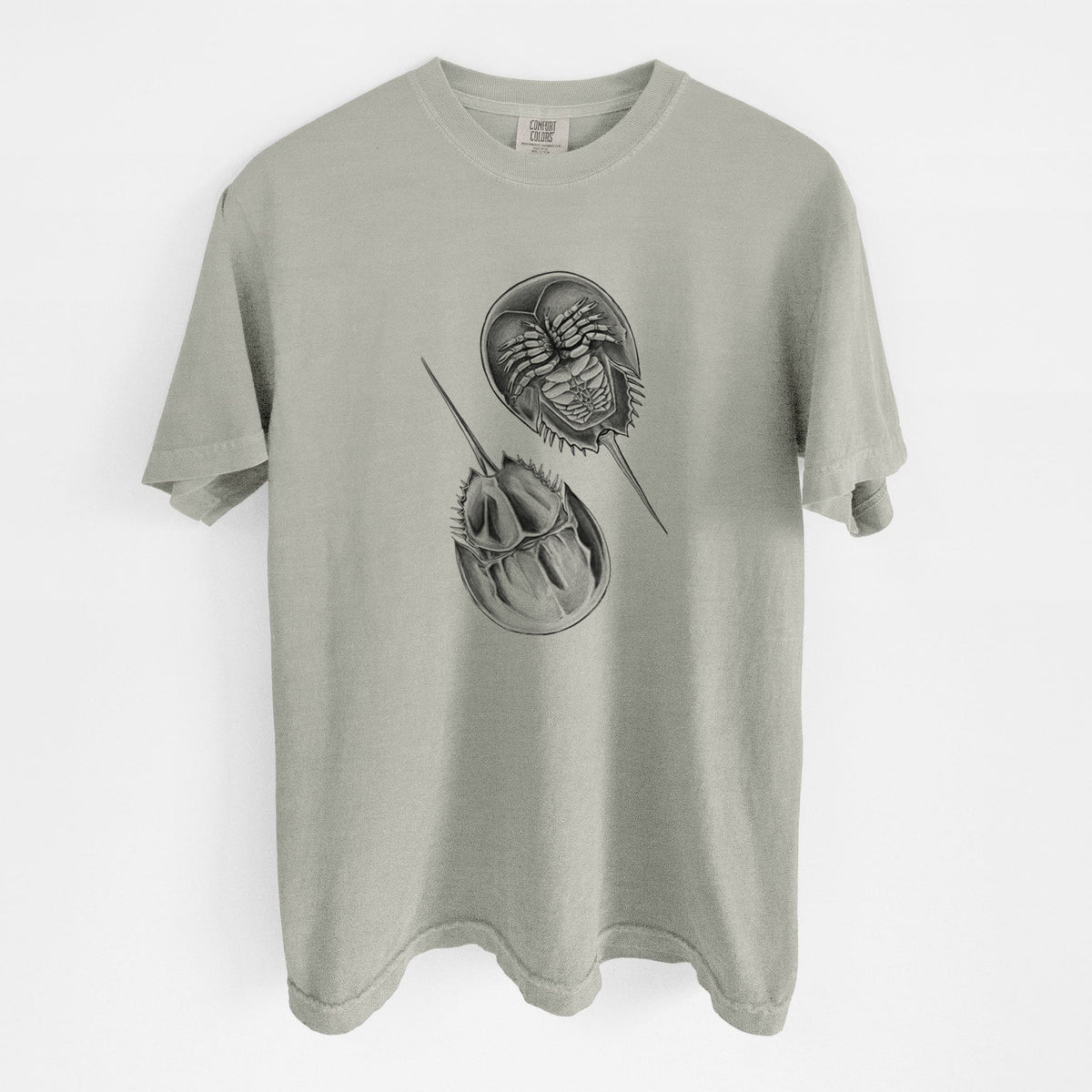 Sandstone beige Comfort Colors t-shirt laid flat, printed with a detailed black ink illustration of two horseshoe crabs.