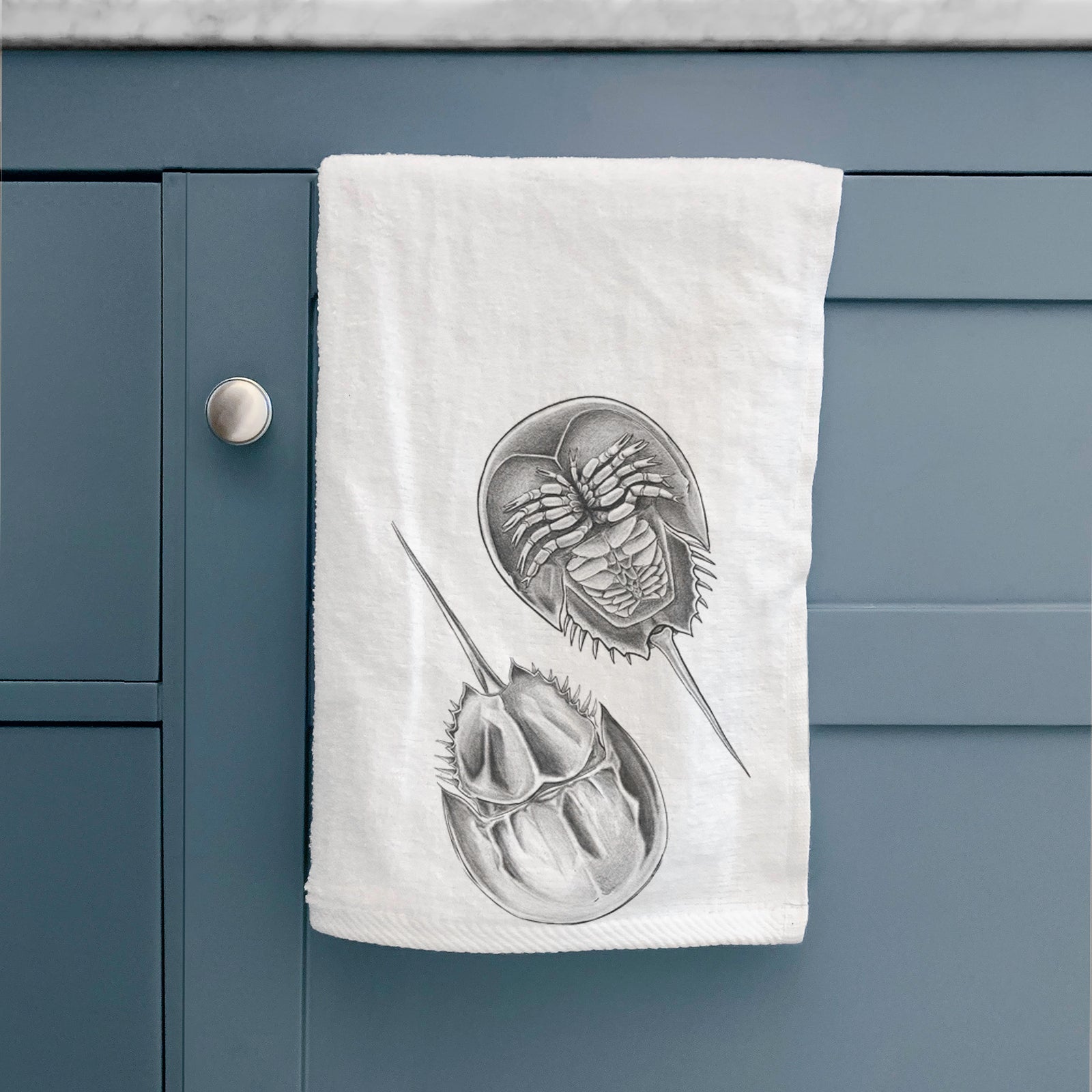 White hand towel printed with a detailed black ink illustration of two horseshoe crabs.