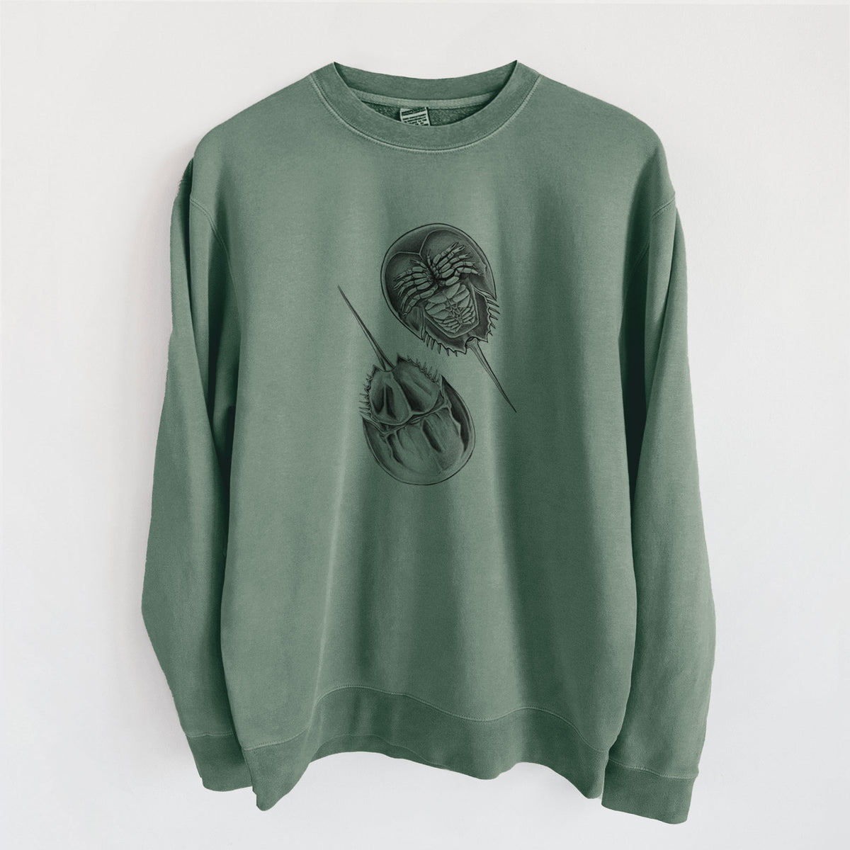Alpine green pigment dyed crewneck sweatshirt laid flat, printed with a detailed black ink illustration of two horseshoe crabs.
