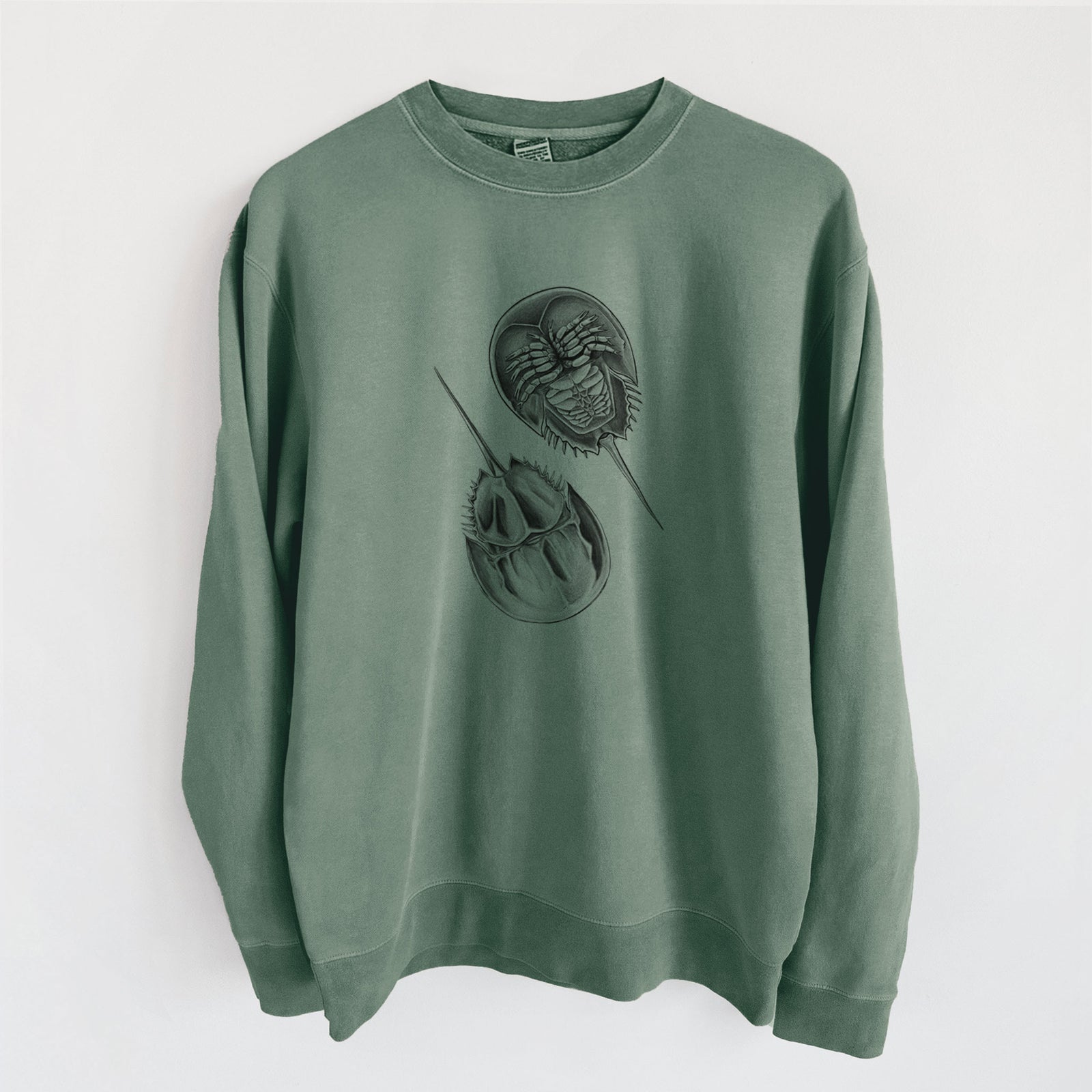 Alpine green pigment dyed crewneck sweatshirt laid flat, printed with a detailed black ink illustration of two horseshoe crabs.