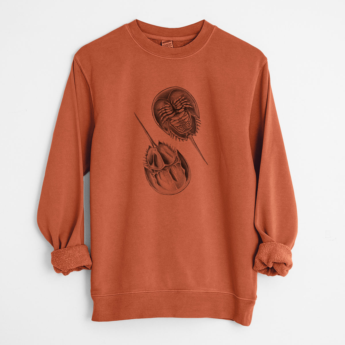 Amber orange pigment dyed crewneck sweatshirt laid flat with the sleeves rolled, printed with a detailed black ink illustration of two horseshoe crabs.