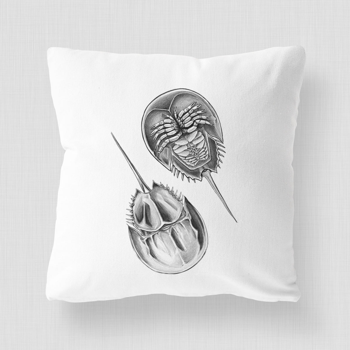 White pillow cover printed with a detailed black ink illustration of two horseshoe crabs.