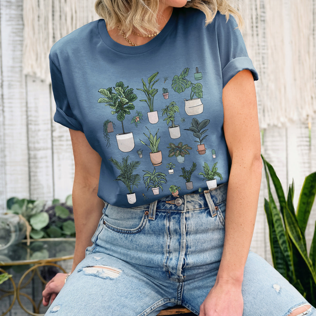 Woman wearing a steel blue lightweight cotton t-shirt printed with a full-color collection of potted houseplants in different pots.
