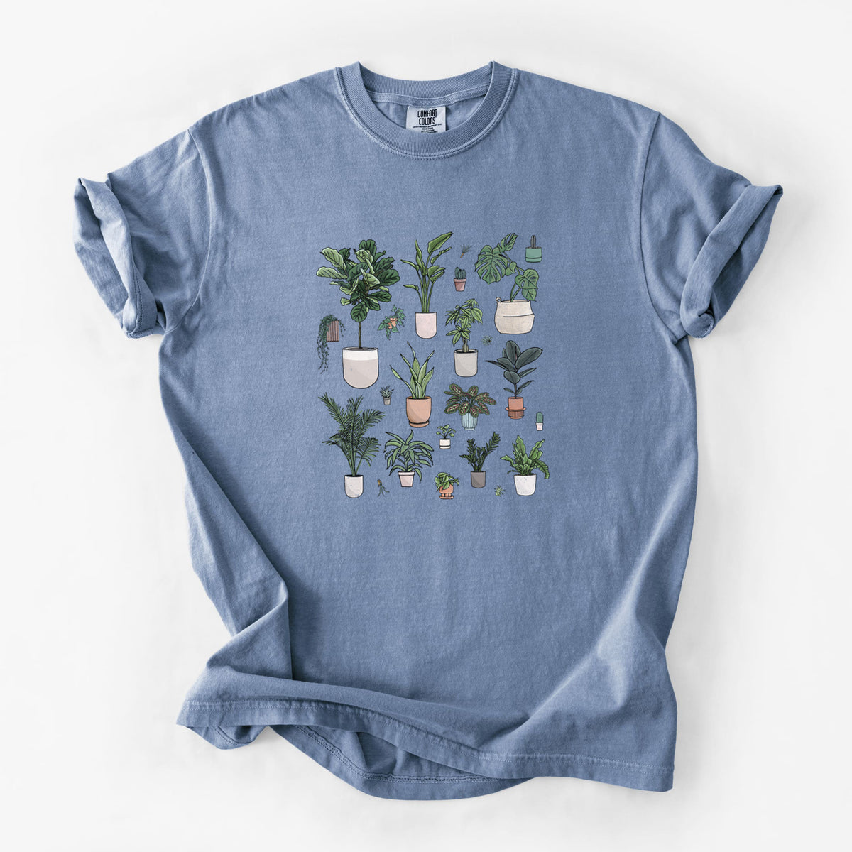 Blue jean Comfort Colors t-shirt laid flat, printed with a full-color collection of potted houseplants in different pots.