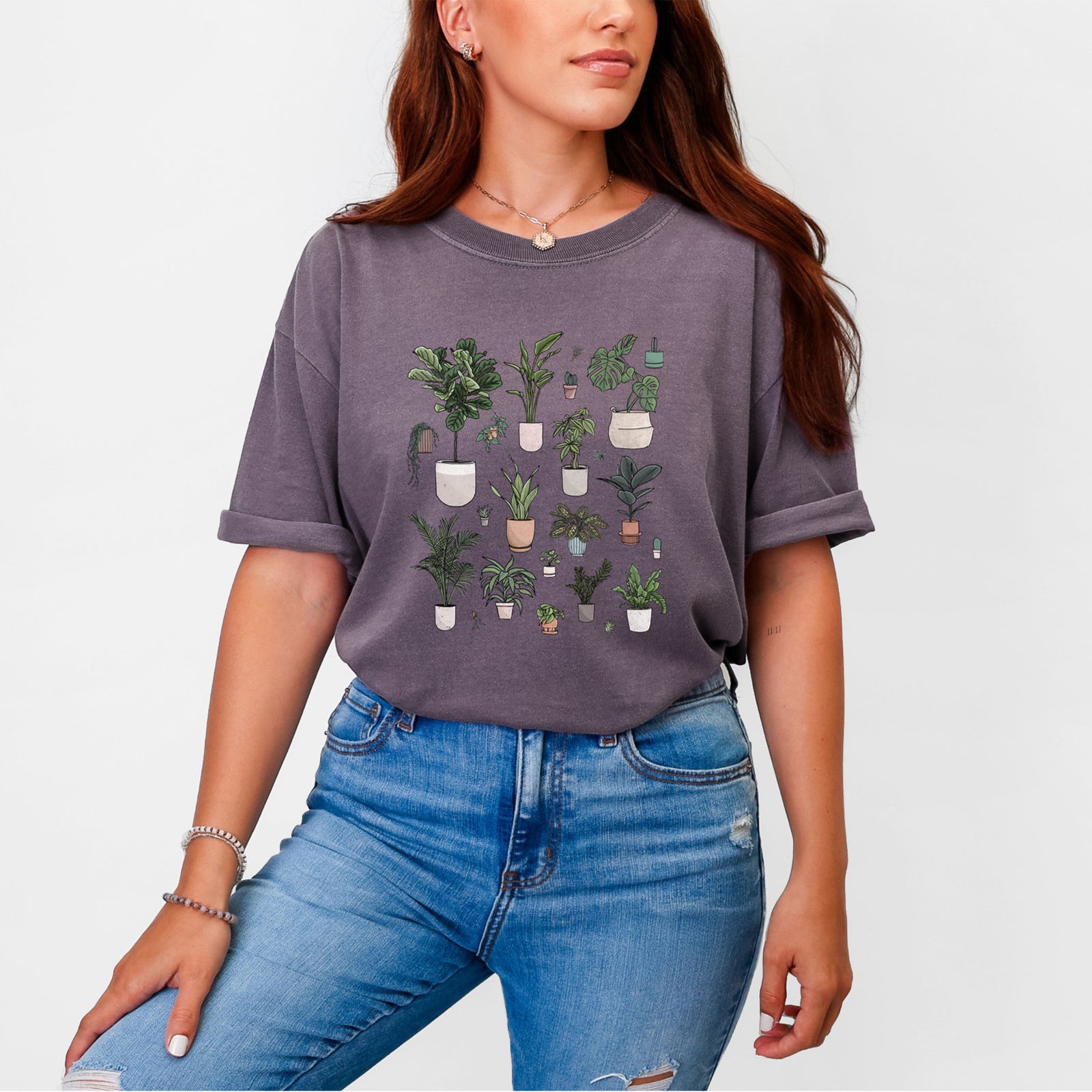 Blue jean Comfort Colors t-shirt laid flat, printed with a full-color collection of potted houseplants in different pots.