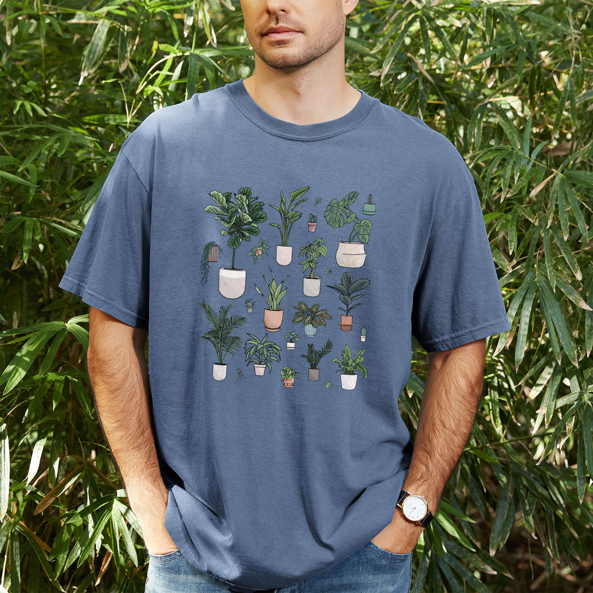 Man wearing a Comfort Colors t-shirt printed with a full-color collection of potted houseplants in different pots, outdoors.