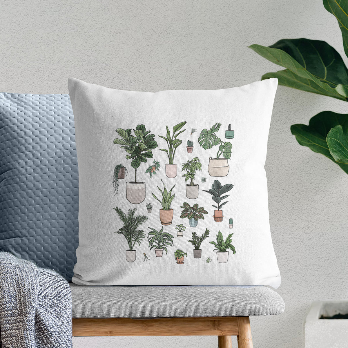 White pillow cover printed with a full-color collection of potted houseplants in different pots, on a bench beside plants.