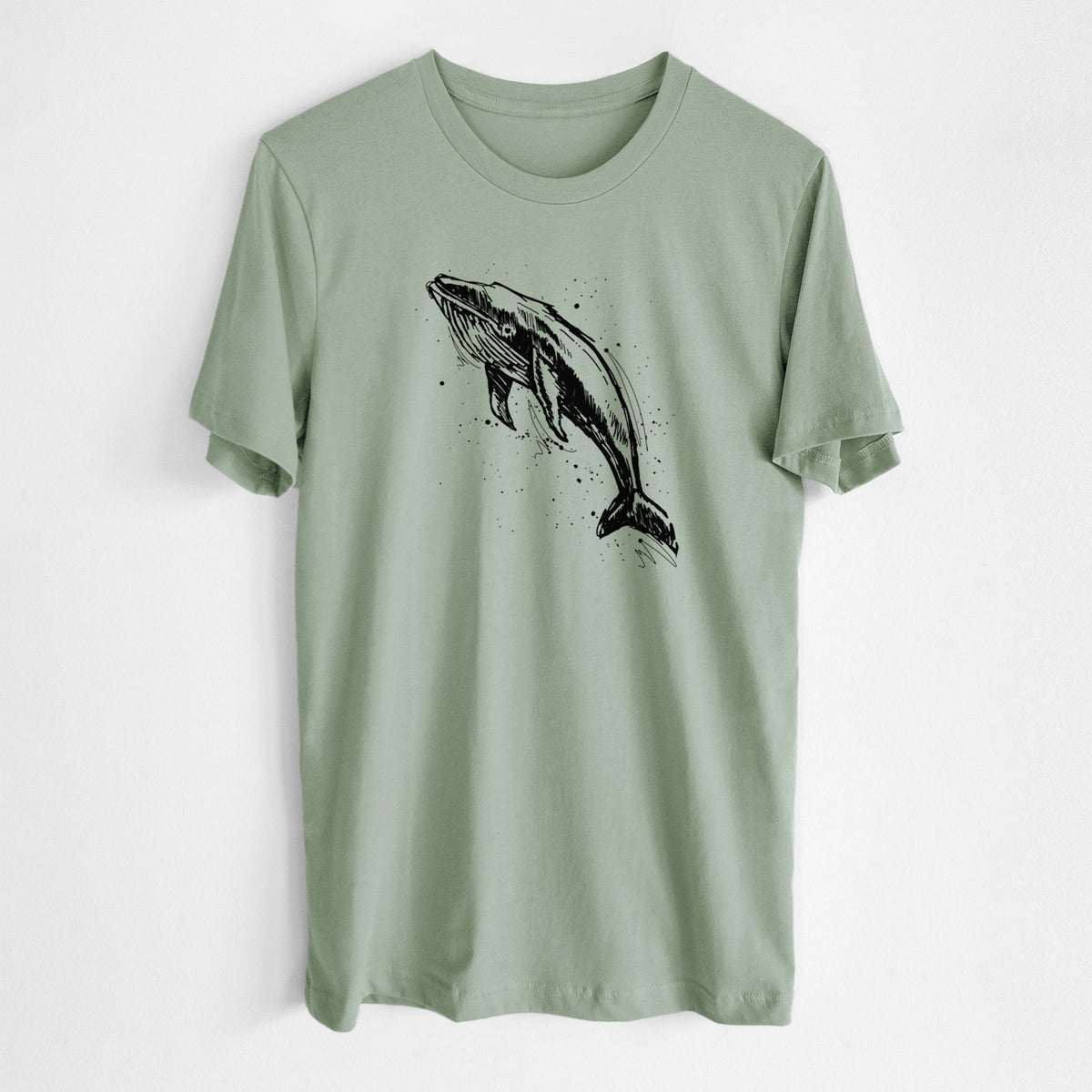 Sage green lightweight cotton t-shirt laid flat, printed with a black ink illustration of a humpback whale diving, with ink splatters.