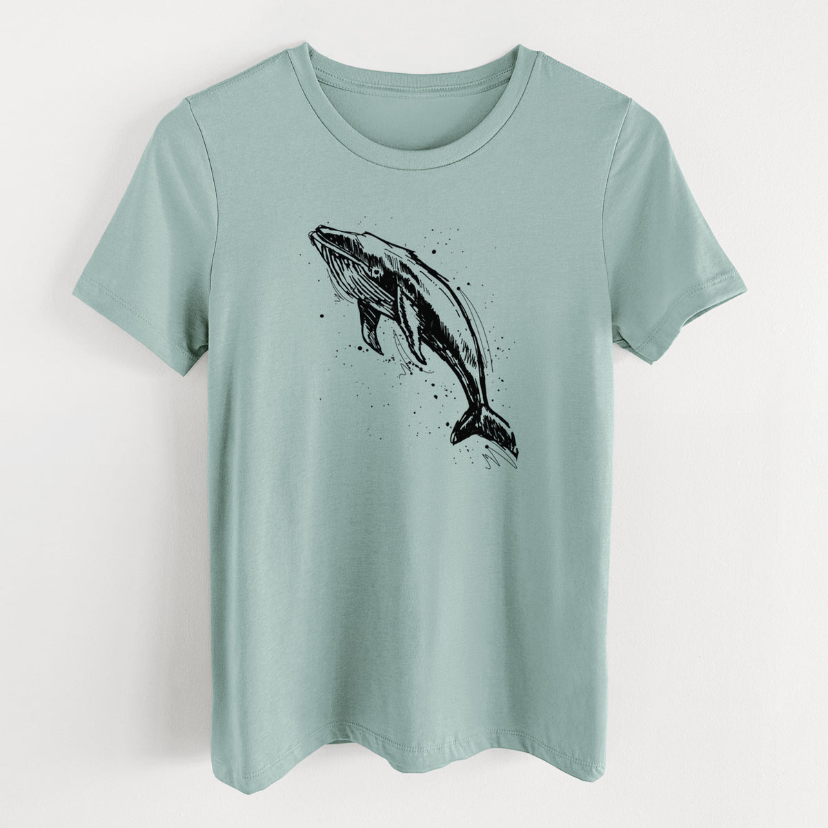 Dusty blue women's relaxed fit cotton t-shirt laid flat, printed with a black ink illustration of a humpback whale diving, with ink splatters.