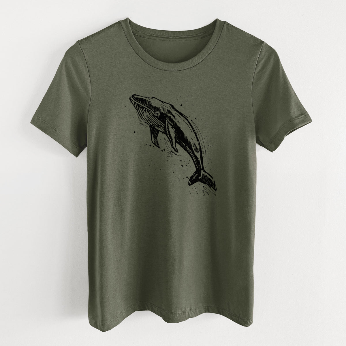 Military green women's relaxed fit cotton t-shirt laid flat, printed with a black ink illustration of a humpback whale diving, with ink splatters.