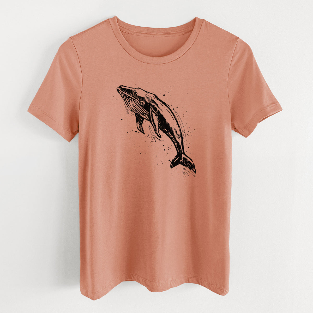 Terracotta orange women's relaxed fit cotton t-shirt laid flat, printed with a black ink illustration of a humpback whale diving, with ink splatters.