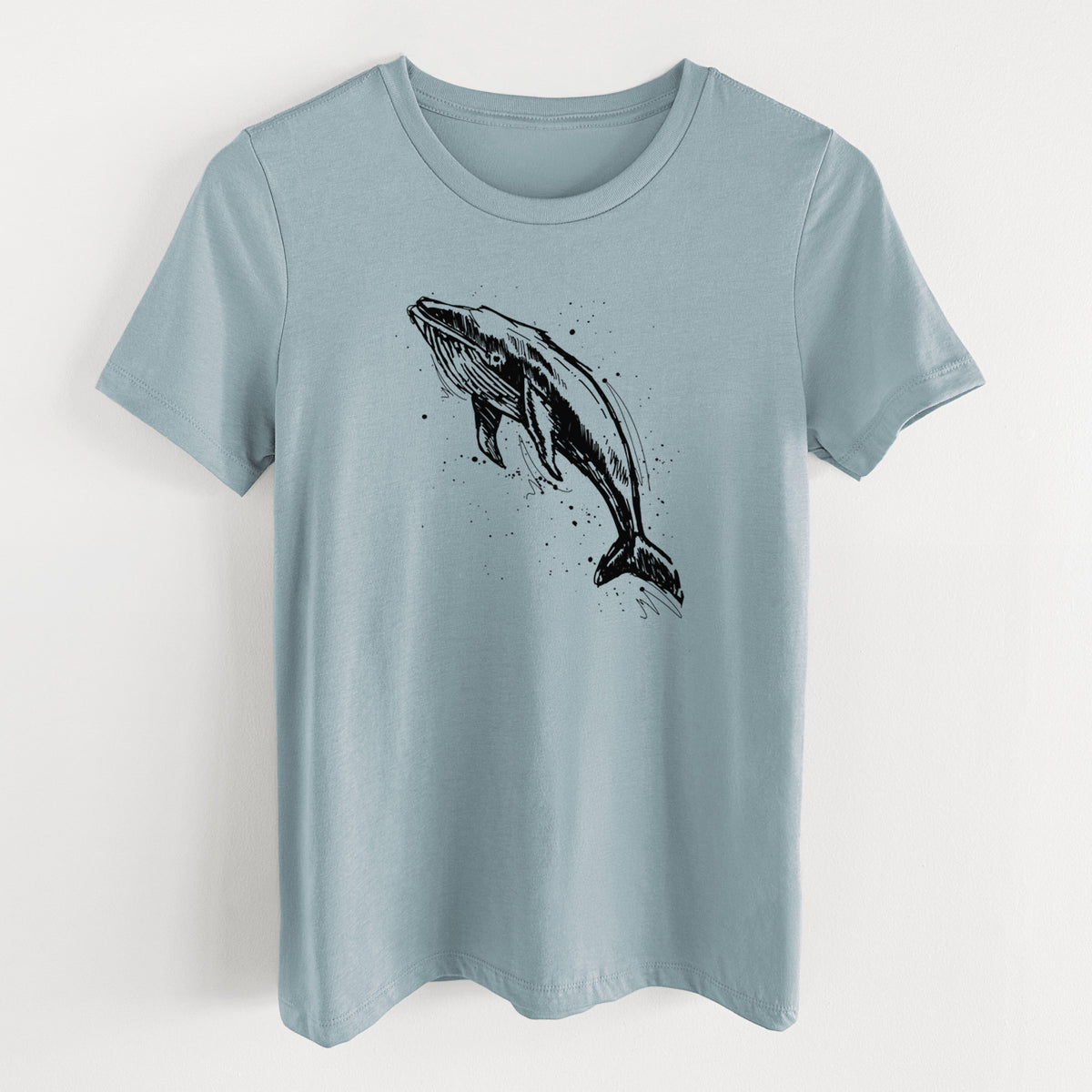 Vintage denim women's relaxed fit cotton t-shirt laid flat, printed with a black ink illustration of a humpback whale diving, with ink splatters.