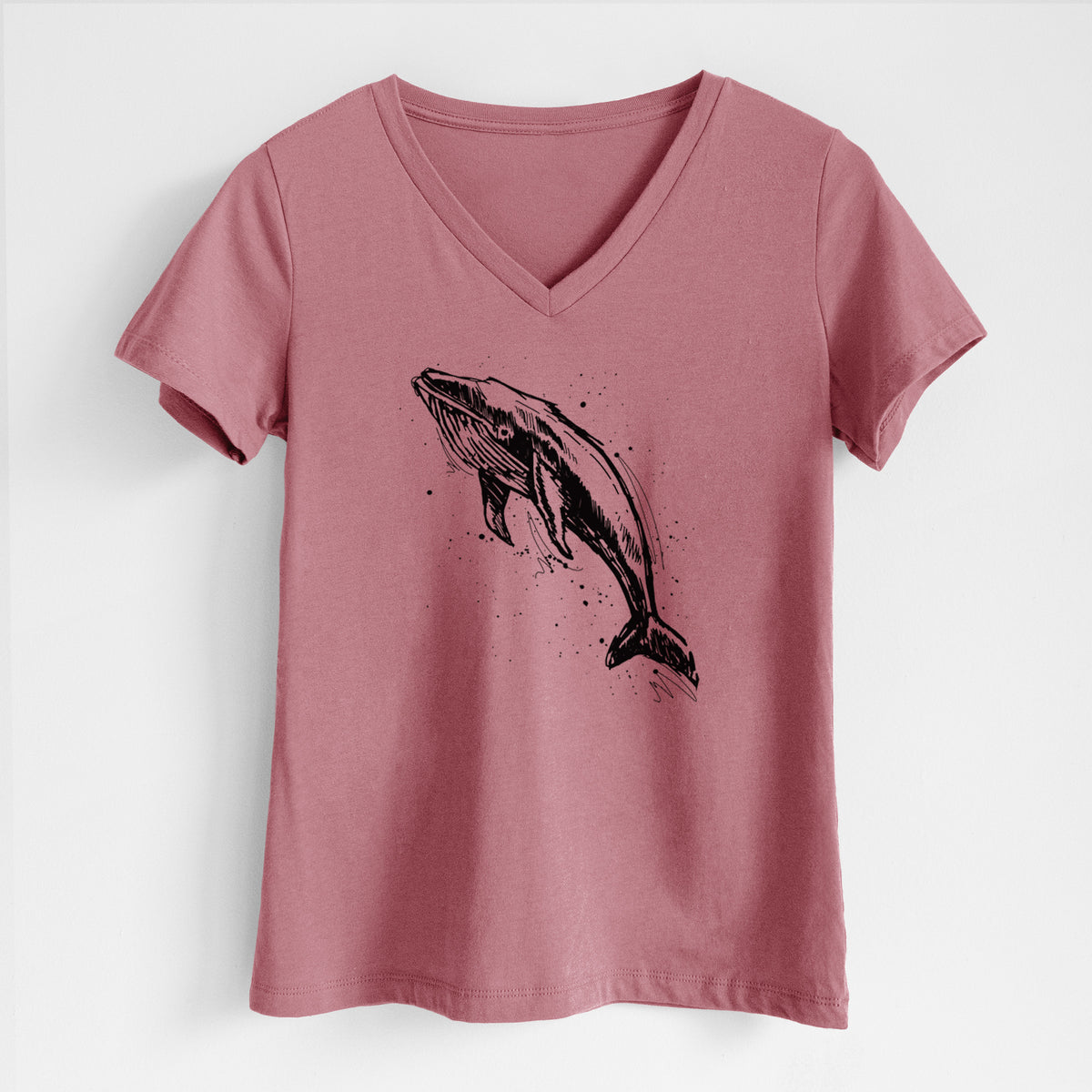 Mauve pink women's relaxed fit cotton V-neck t-shirt laid flat, printed with a black ink illustration of a humpback whale diving, with ink splatters.