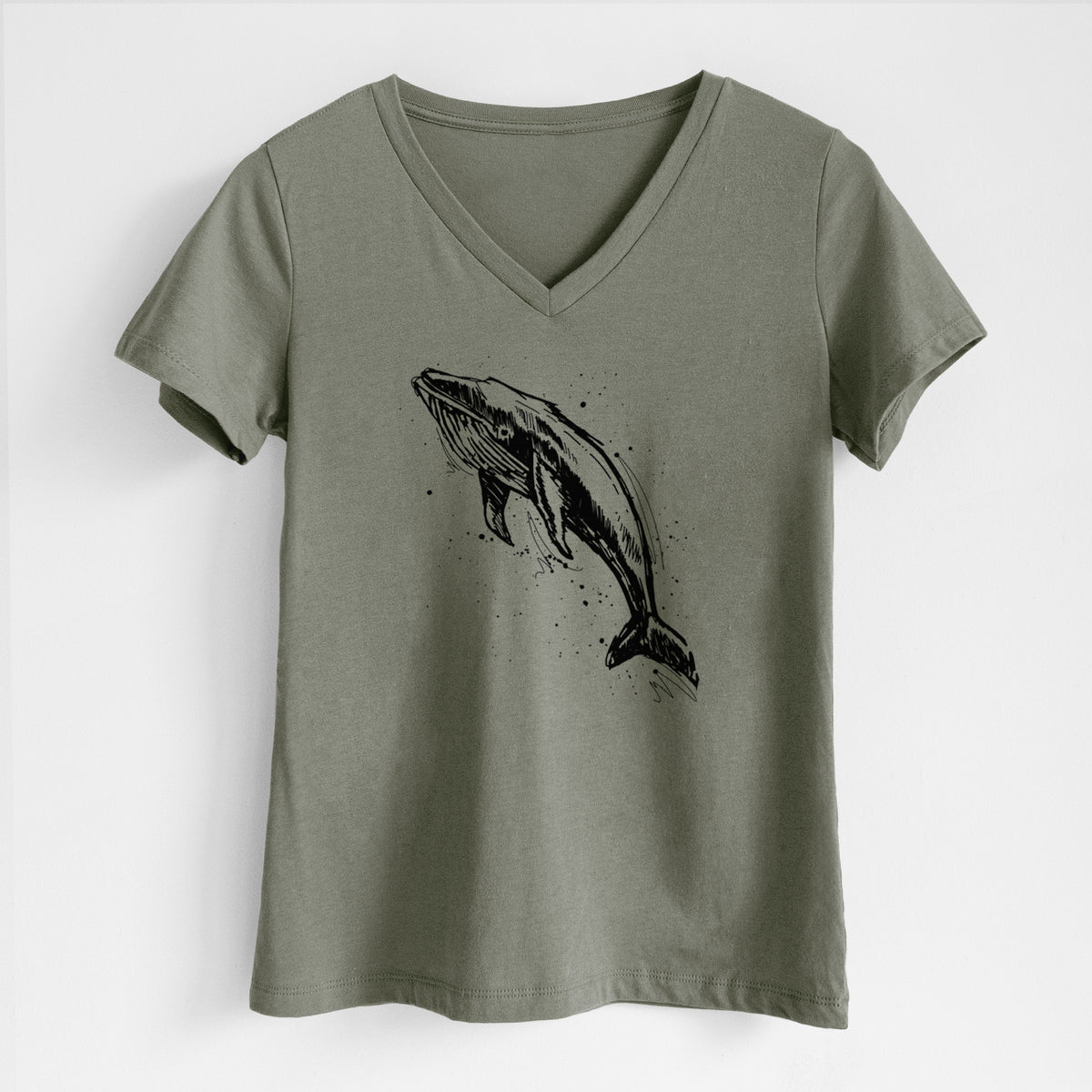 Military green women's relaxed fit cotton V-neck t-shirt laid flat, printed with a black ink illustration of a humpback whale diving, with ink splatters.