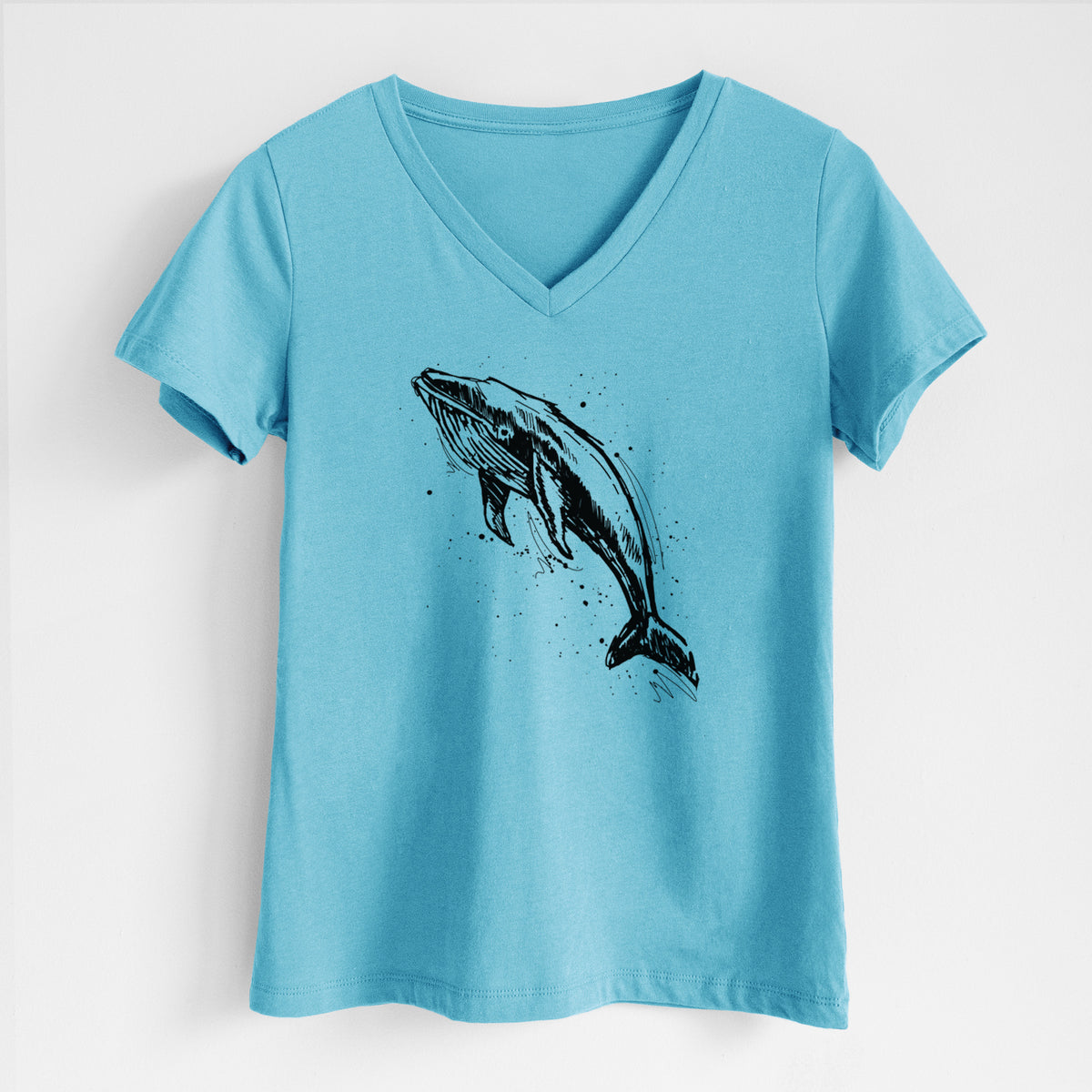 Turquoise women's relaxed fit cotton V-neck t-shirt laid flat, printed with a black ink illustration of a humpback whale diving, with ink splatters.