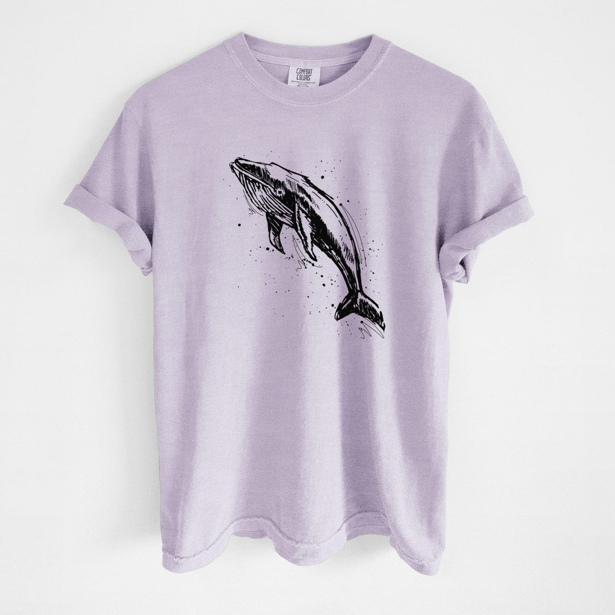 Orchid purple Comfort Colors t-shirt laid flat, printed with a black ink illustration of a humpback whale diving, with ink splatters.