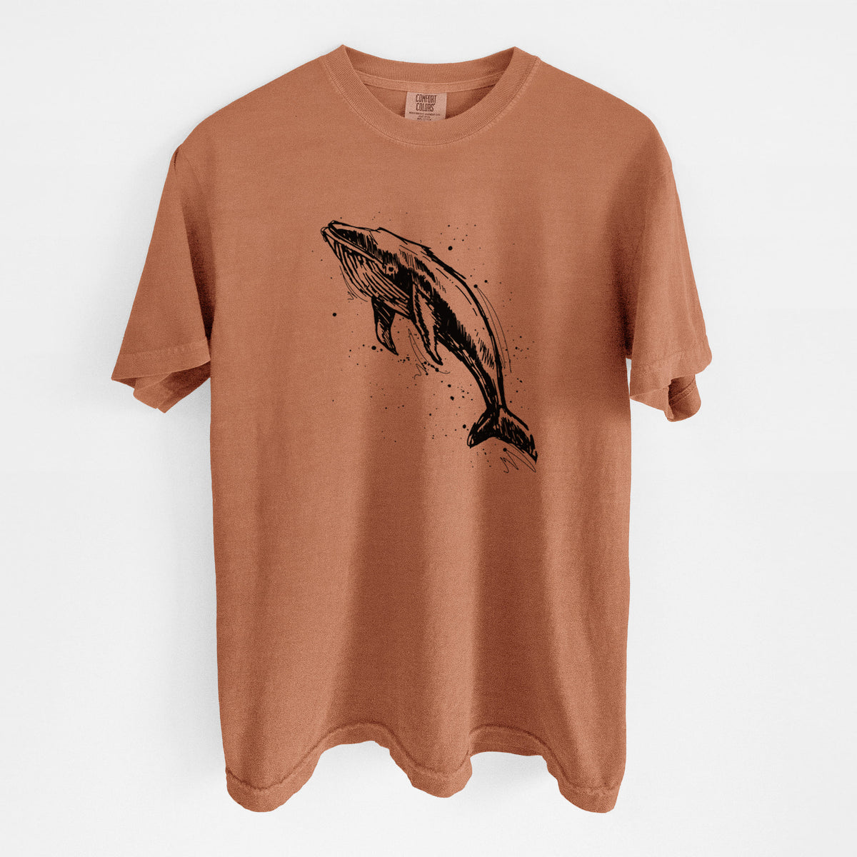 Yam burnt orange Comfort Colors t-shirt laid flat, printed with a black ink illustration of a humpback whale diving, with ink splatters.