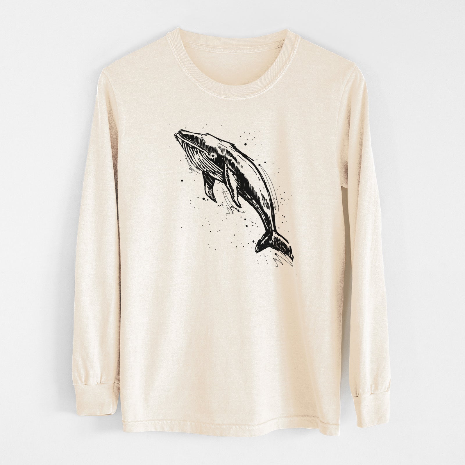 Ivory Comfort Colors long sleeve shirt laid flat, printed with a black ink illustration of a humpback whale diving, with ink splatters.
