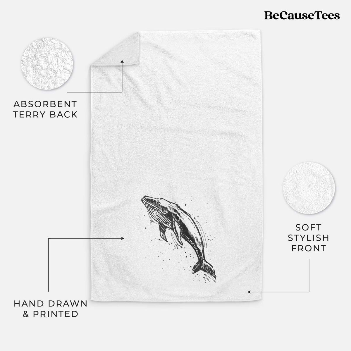 White hand towel printed with a black ink illustration of a humpback whale diving, with ink splatters.