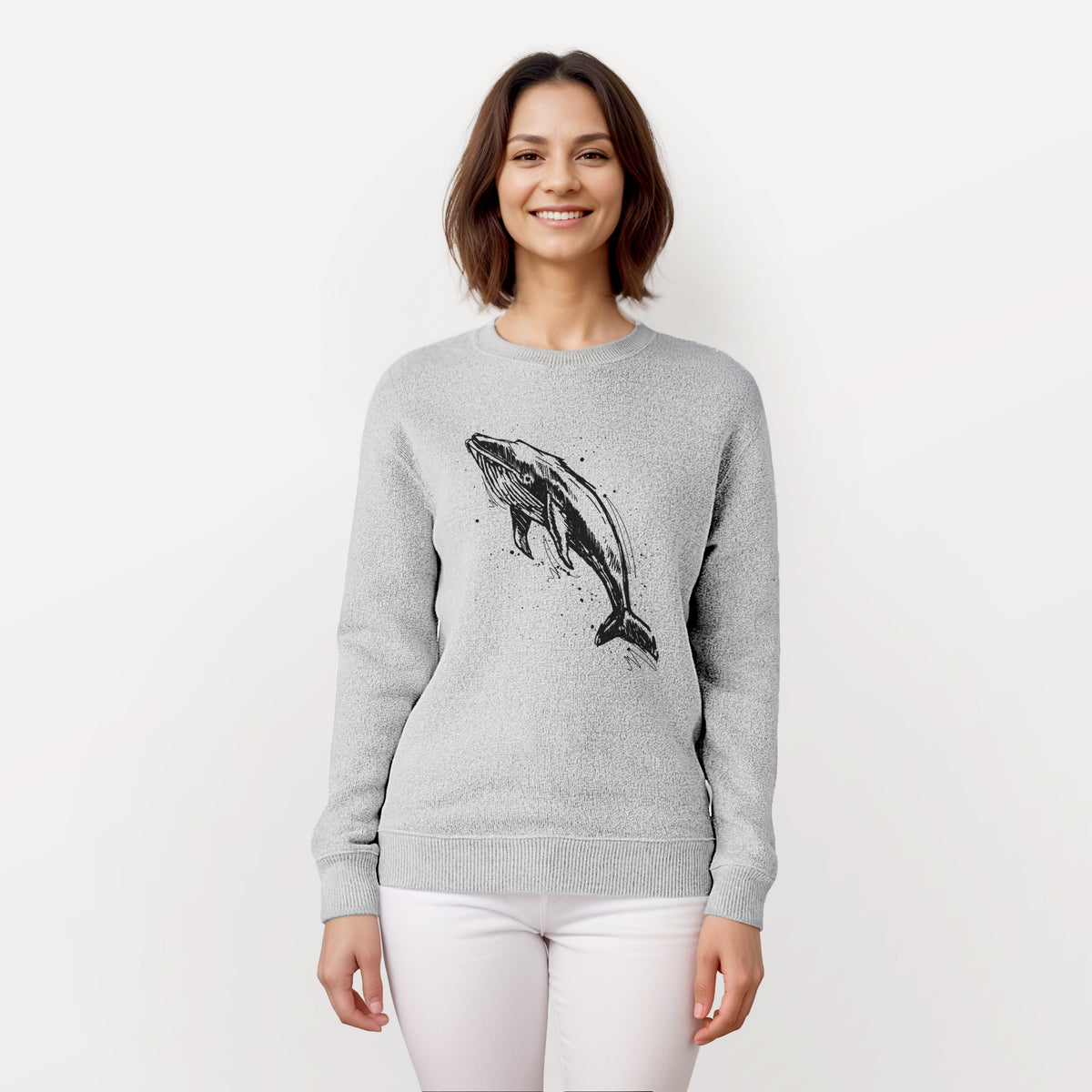 Woman wearing a knit sweatshirt printed with a black ink illustration of a humpback whale diving, with ink splatters.