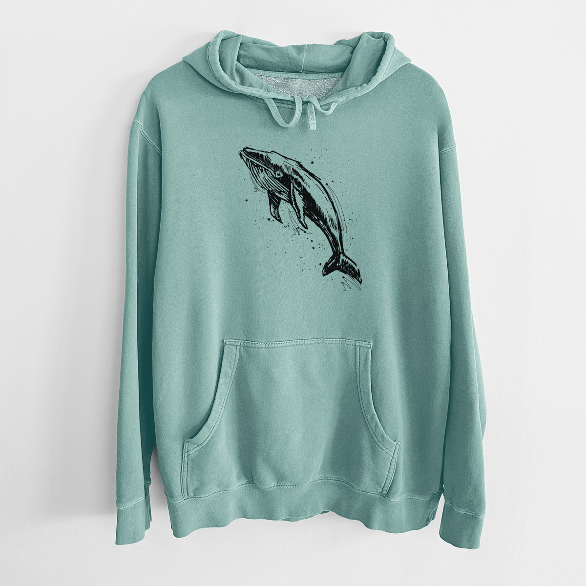 Mint green pigment dyed hoodie laid flat, printed with a black ink illustration of a humpback whale diving, with ink splatters.