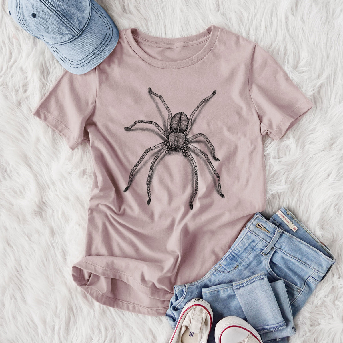 Women's relaxed fit cotton t-shirt printed with a detailed black ink illustration of a huntsman spider with long legs spread, styled flat on a white faux fur rug with jeans.